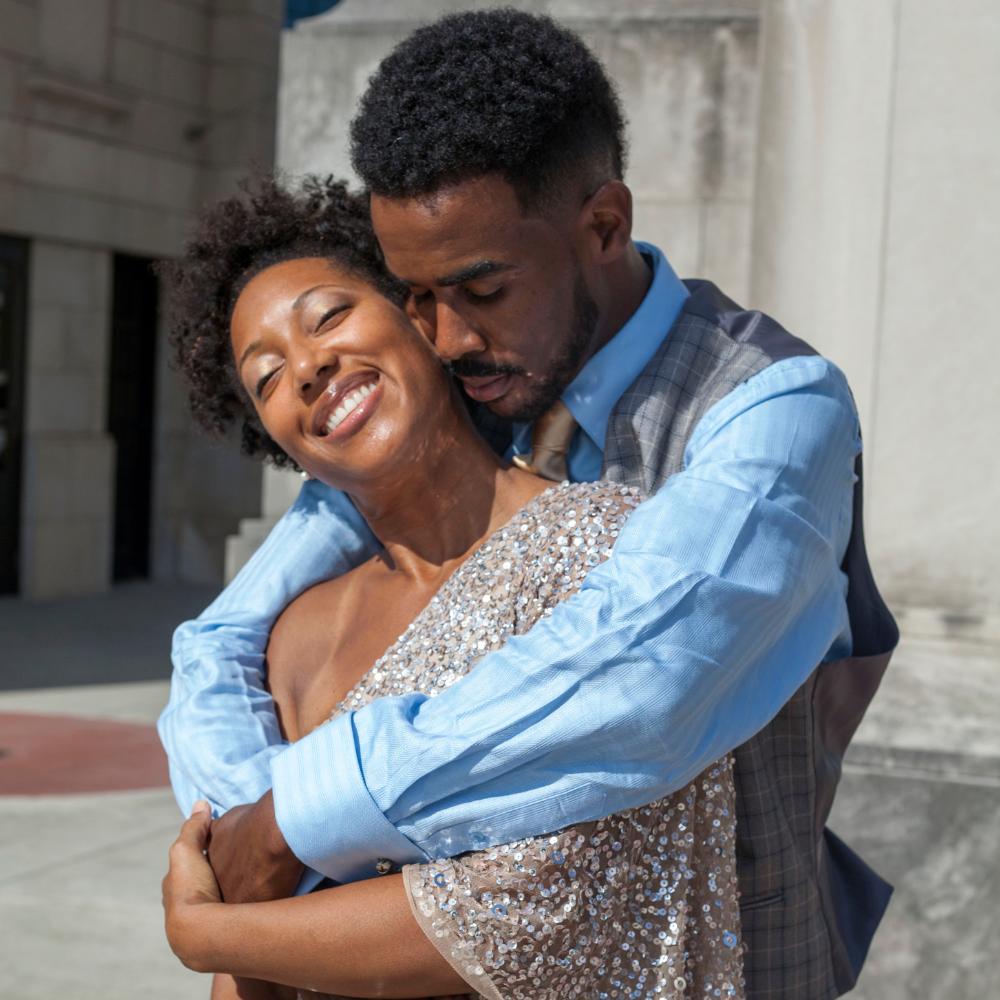 Man hugging smiling woman from behind.